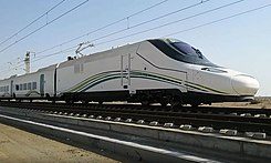 Tren alta velocidad Talgo 350 SRO La Meca - Medina Tren de alta velocidad en movimiento sobre rieles en un paisaje desértico.