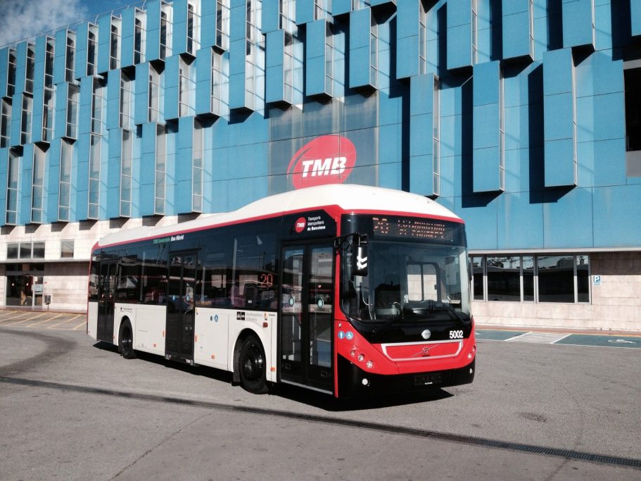 Autobús Volvo 7900 Hybrid TMB Barcelona Autobús urbano rojo y blanco estacionado frente a un edificio moderno.
