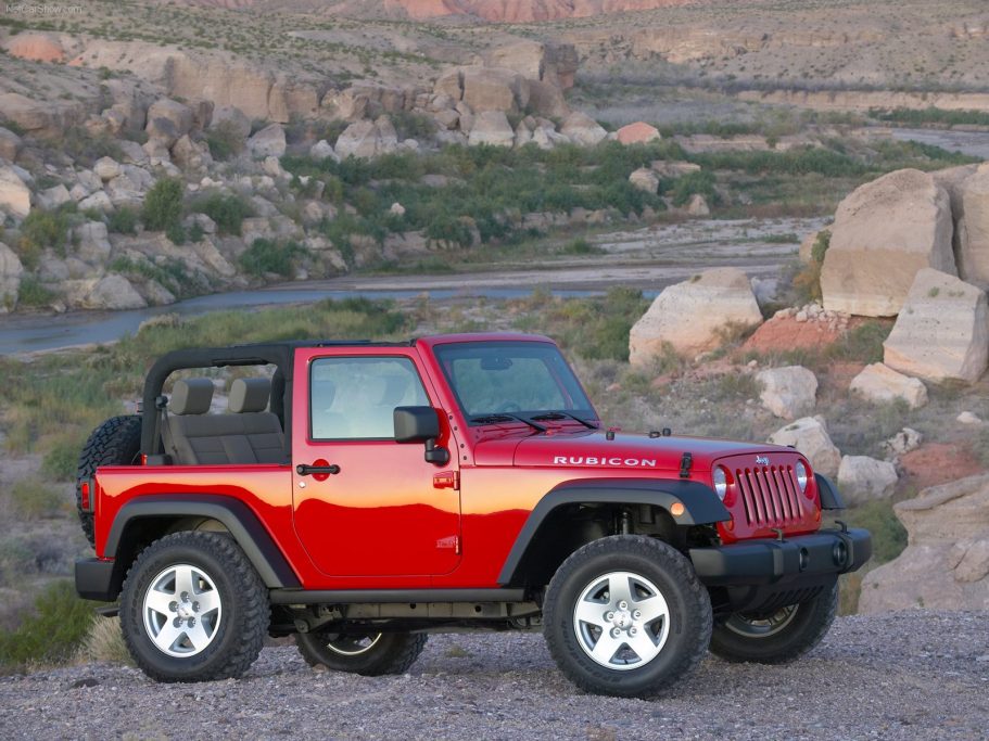 Todoterreno Jeep Wrangler Coche todoterreno rojo estacionado junto a un paisaje rocoso y un camino.