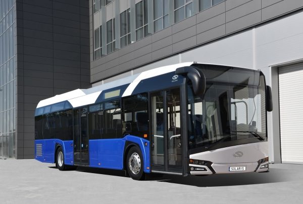 Autobús Solaris Urbino 12 Electric Autobús urbano moderno con colores azul y blanco, estacionado frente a un edificio.