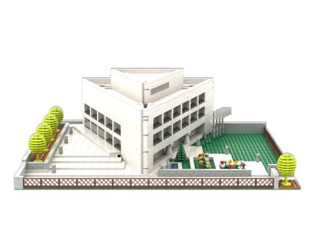 Edificio moderno con jardín y árboles, rodeado de una valla.